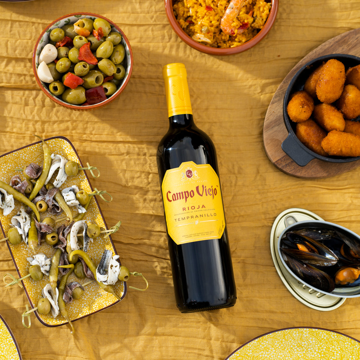 Bottle of Campo Viejo wine surrounded by tapas on a wooden table