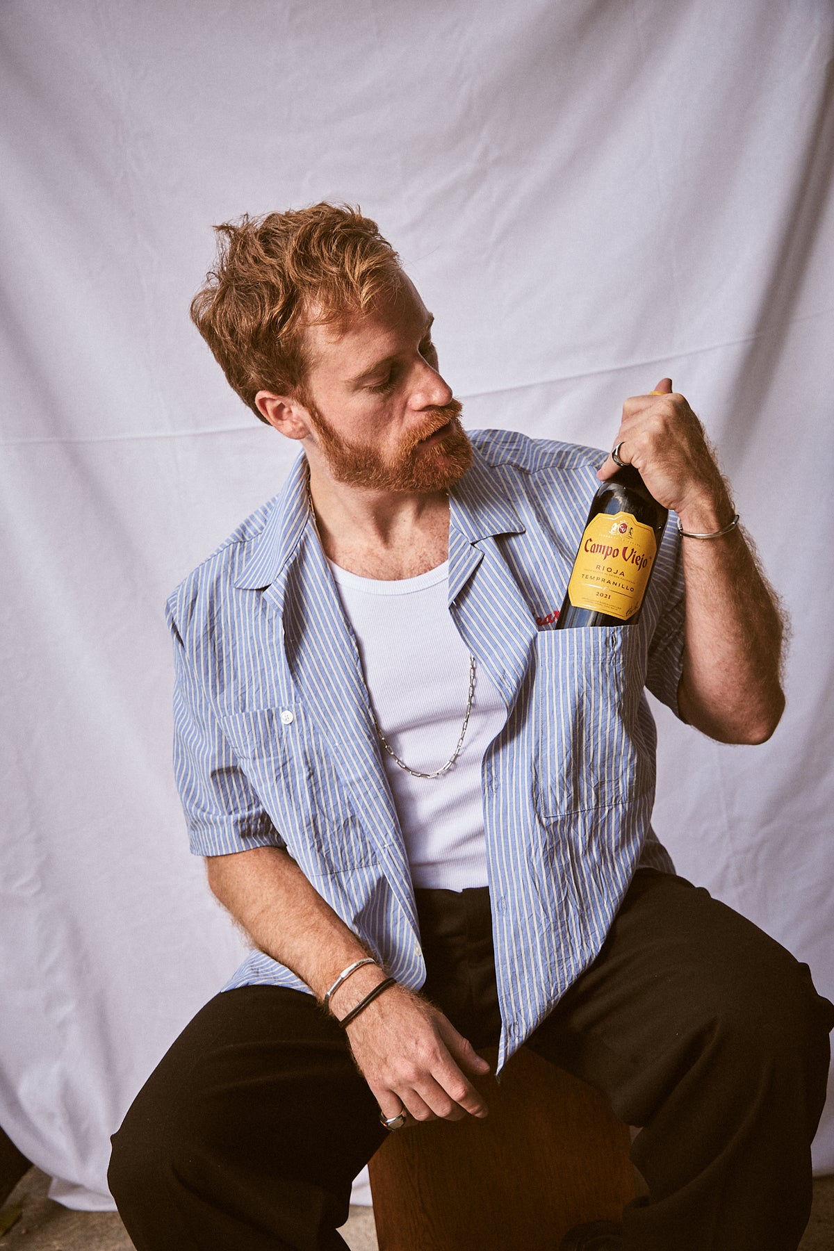 Man holding a bottle against a plain background